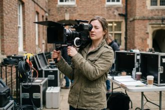 Étudiante en école de cinéma tenant une caméra professionnelle sur un plateau de tournage universitaire